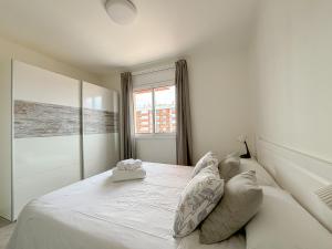 a white bedroom with a large white bed with pillows at Clauhomes Suite Center in Tarragona
