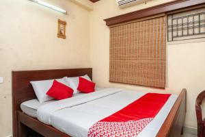 um quarto com uma cama com almofadas vermelhas e uma janela em OYO Sr Pradeep Park em Chennai