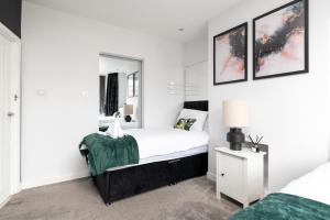 a white bedroom with a bed and a mirror at Cosy 2BR Bungalow + Parking in Northampton