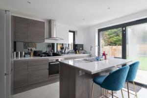 una cocina con armarios de madera y taburetes de barra azul en Cosy 2BR Bungalow + Parking, en Northampton