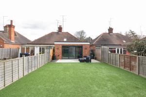 a courtyard with green grass in front of a house at Cosy 2BR Bungalow + Parking in Northampton