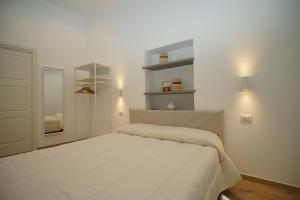 een witte slaapkamer met een bed en een spiegel bij Les pieds dans l'eau Vernazza in Vernazza