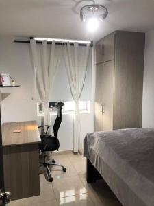 a bedroom with a bed and a desk and a chair at Hermoso Apartamento en la mejor zona de la ciudad in Armenia +9 photos