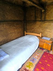 - une chambre avec un lit doté d'une tête de lit en bois et d'une table de chevet dans l'établissement Konak Jezero - Drvene Kućice na Privatnom Jezeru, à Šabac