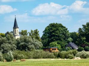 una iglesia con un campanario en la distancia con un campo en Elbauen-Chalet, en Cumlosen