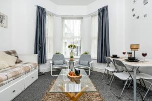 ein Wohnzimmer mit einem Sofa, einem Tisch und Stühlen in der Unterkunft Cosy Wirral home near Liverpool with Free Parking! in Birkenhead