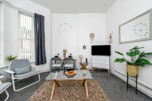 uma sala de estar com uma mesa e cadeiras e uma televisão em Cosy Wirral home near Liverpool with Free Parking! em Birkenhead