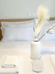 un jarrón blanco con una pluma en la cama en John‘s house, en Atenas