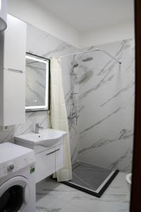 a white bathroom with a shower and a sink at Vila Emi in Durrës