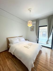 Un dormitorio con una gran cama blanca y una ventana en John‘s house, en Atenas