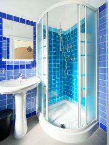 a blue tiled bathroom with a shower and a sink at Hotel Reale in Rimini +64 photos
