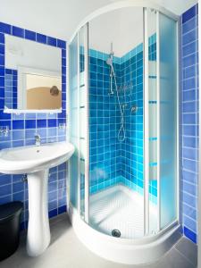 uma casa de banho em azulejos azuis com um chuveiro e um lavatório. em Hotel Reale em Rimini