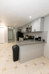 a kitchen with white cabinets and a trash can at Bright 2-Bed Haven Close to NYC in Jersey City