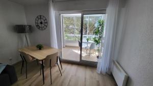 ein Wohnzimmer mit einem Tisch und einer Glasschiebetür in der Unterkunft Appartement de 50 m2 cosy et moderne à 100 m de la plage in Saint-Mandrier-sur-Mer