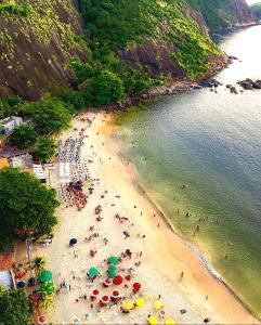 Pê na areia Loft Praia de Itaipú في Itaipu: زحمة الناس على شاطئ فيه مظلات