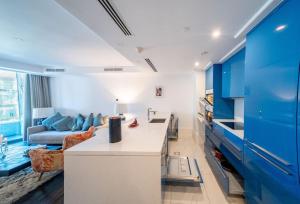 cocina y sala de estar con armarios azules y sofá en Amman Abdali Boulevard l Luxury l 1 BR Condo, en Amán