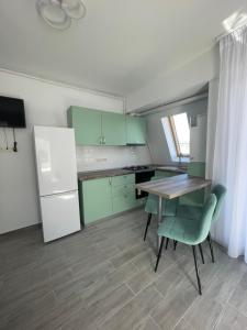 eine Küche mit grünen Schränken sowie einem Tisch und Stühlen in der Unterkunft Marisah Residence #6 in Otopeni