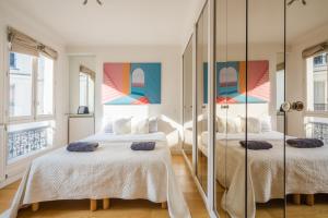 - 2 lits dans une chambre avec 2 miroirs dans l'établissement Appartement Tour Eiffel & Trocadéro, à Paris