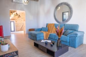 a living room with a blue couch and a mirror at Radiant 5 BR family home with jacuzzi + roof deck in Palau de Santa Eulalia