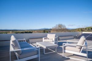 een terras met stoelen en een salontafel op een dak bij Radiant 5 BR family home with jacuzzi + roof deck in Palau de Santa Eulalia