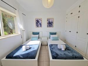 Dos camas en una habitación con paredes blancas. en Apartment Oasis Park AL, en Portimão