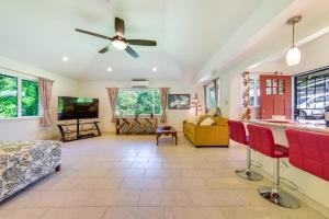 a living room with a ceiling fan and red chairs at Bright Haiku Studio Patio and Rainforest View in Haiku