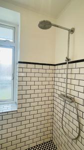 a shower in a white tiled bathroom with a window at ApartmentInCopenhagen Apartment 1599 in Hellerup