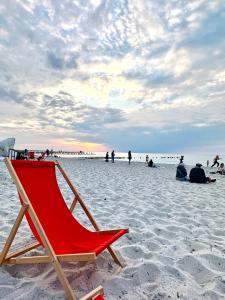 a red beach chair sitting on a sandy beach at Schwalbennest in Zingst