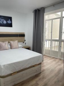 a bedroom with a large bed and a large window at Apartamento Torre del Castillo in Sanlúcar de Barrameda