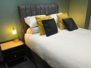 a bed with black and yellow pillows and a lamp at The Butchers Arms - Grill Pub and Accommodation in Merthyr Tydfil