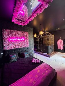 um quarto com uma cama roxa e iluminação rosa em Sweet SECRET'S JACUZZI em Le Breuil