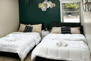 zwei Betten in einem Zimmer mit grüner Wand in der Unterkunft Modern Home Near Ontario Airport in Ontario