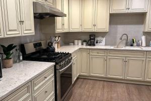 a kitchen with white cabinets and a stove top oven at North Pomona Home Near Claremont Colleges in Pomona