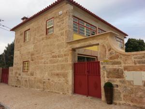 a stone house with red doors and a red garage at Quinta da Cardal in Vila Verde