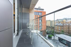 einen Balkon mit einem Stuhl und Stadtblick in der Unterkunft Gorgeous Central 2BR Flat, Belgravia, Chelsea in London