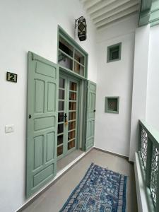 a hallway with a green door and a rug at La Maison des Amis in Fès