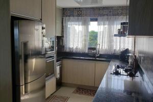a kitchen with a stainless steel refrigerator and a window at Apartamento Sorocotuba Guaruja in Guarujá