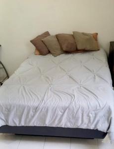 Una cama blanca con almohadas encima. en Apartamento Las Flores Mérida en Mérida