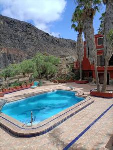 a swimming pool in front of a building with palm trees at Casa de campo con piscina in Las Palmas de Gran Canaria