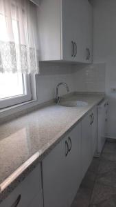 une cuisine blanche avec un évier et une fenêtre dans l'établissement Bodrum Family Apartments, à Bodrum City