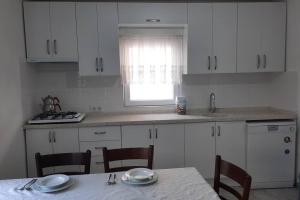 - une cuisine avec des placards blancs, une table et des chaises dans l'établissement Bodrum Family Apartments, à Bodrum City