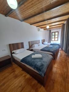 two beds in a room with wooden ceilings and wood floors at Hotel Demaj in Berat