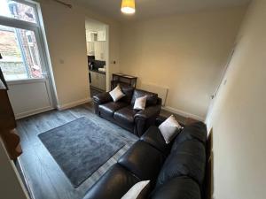 a living room with a leather couch and two couches at 3 Bedroom Home From Home, Crewe in Crewe
