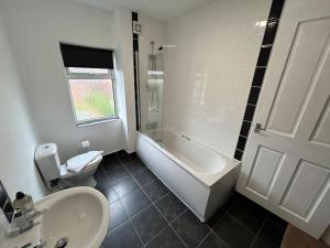 a bathroom with a tub and a toilet and a sink at 3 Bedroom Home From Home, Crewe in Crewe
