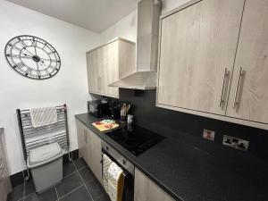 a small kitchen with a clock on the wall at 3 Bedroom Home From Home, Crewe in Crewe