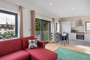 a living room with a red couch and a kitchen at Modern One Bedroom Flat in Morden SM4, London in Morden