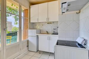 une cuisine avec des placards blancs et une fenêtre dans l'établissement Charming apartment with balcony and panoramic view, à Aix-en-Provence