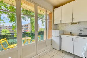 Il comprend une cuisine avec des placards blancs et un balcon avec une table. dans l'établissement Charming apartment with balcony and panoramic view, à Aix-en-Provence