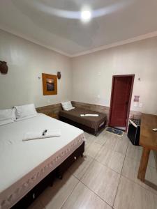 a bedroom with two beds and a desk in it at Pousada das Canoas in Acaraú
