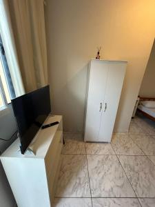 a room with a white cabinet and a television at Pousada Quartos vcp in Viracopos